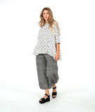 model in a barrel leg stripe pant with a white button down with black dots