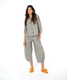 A woman modeling a matching two-piece set consisting of a grey button-up shirt and cropped pants in a with a yellow textured dot pattern. Paired with yellow shoes, on a white studio background.