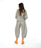 A woman modeling a matching two-piece set consisting of a grey button-up shirt and cropped pants in a with a yellow textured dot pattern. Paired with yellow shoes, on a white studio background.
