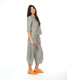 A woman modeling a matching two-piece set consisting of a grey button-up shirt and cropped pants in a with a yellow textured dot pattern. Paired with yellow shoes, on a white studio background.