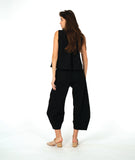 model in a black sleeveless blouse with a textured dot pattern. worn with a barrel leg matching pant