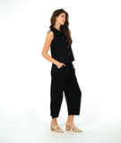 model in a black sleeveless blouse with a textured dot pattern. worn with a barrel leg matching pant