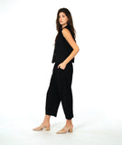 model in a black sleeveless blouse with a textured dot pattern. worn with a barrel leg matching pant