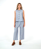 model in a sleeveless blouse with a soft blue and white stripe with a yellow textured dot pattern. worn with a wide leg matching pant and brown shoes