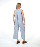 model in a sleeveless blouse with a soft blue and white stripe with a yellow textured dot pattern. worn with a wide leg matching pant and brown shoes