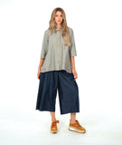 model in a wide leg chambray pant, with a long button down blouse in a grey and white stripe with a yellow  texture dot detail. 