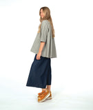 model in a wide leg chambray pant, with a long button down blouse in a grey and white stripe with a yellow  texture dot detail. 