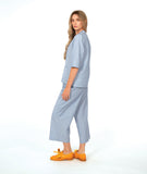 model in a wide leg cargo pant, worn with a matching button down blouse in a blue and white stripe with a yellow texture dot detail.  blouse has external squared pockets and  3/4 sleeve