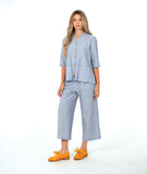 model in a wide leg cargo pant, worn with a matching button down blouse in a blue and white stripe with a yellow texture dot detail.  blouse has external squared pockets and  3/4 sleeve