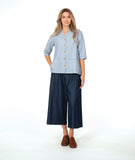 model in a wide leg chambray pant, with a long button down blouse in a blue and white stripe with a yellow texture dot detail.  blouse has external squared pockets and  3/4 sleeve