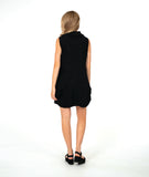 model in a black sleeveless dress with an oversized cowl neck. dress is black with small textured dots, and has side seam pockets, princess seams and shaping tucks at the hips