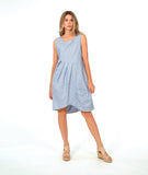 model in a sleeveless, knee length dress with an asymmetrical skirt. dress is a soft blue and white stripe with a small yellow textured dot print