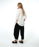 model in a white pullover top with a textured swirl print, round neck, and splits at the hips and front center. worn with a matching black pant with a slight barrel leg