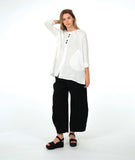 model in a white pullover top with a textured swirl print, round neck, and splits at the hips and front center. worn with a matching black pant with a slight barrel leg