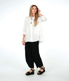 model in a white pullover top with a textured swirl print, round neck, and splits at the hips and front center. worn with a matching black pant with a slight barrel leg