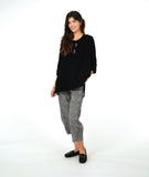 model in a black pullover top with a textured swirl print, round neck, and splits at the hips and front center. worn with a black and white striped pant with a slight barrel leg