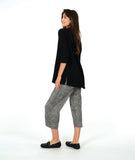 model in a black pullover top with a textured swirl print, round neck, and splits at the hips and front center. worn with a black and white striped pant with a slight barrel leg