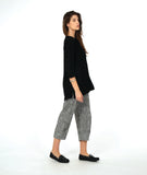 model in a black pullover top with a textured swirl print, round neck, and splits at the hips and front center. worn with a black and white striped pant with a slight barrel leg