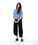 model in a short sleeve blue button down with a black wide leg barrel pant