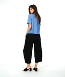 model in a short sleeve blue button down with a black wide leg barrel pant
