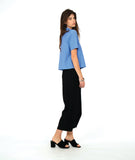 model in a short sleeve blue button down with a black wide leg barrel pant