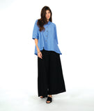 model in a blue color button down with a swirl texture. blouse has 3/4 sleeves and oversized rounded pockets at the hip. Worn with a wide leg black pant
