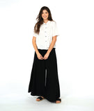 model in a short sleeve white button down with a black wide leg pant