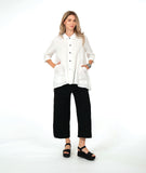 model in a white button down with a swirl texture. blouse has 3/4 sleeves and oversized rounded pockets at the hip. Worn with a wide leg black pant with the same texture