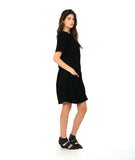 model in a black knee length dress with short sleeves and a round neckline. dress has a swirl texture and a diagonal seam across the body with a hidden seam pocket on the right