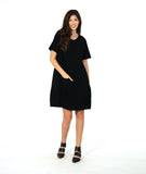 model in a black knee length dress with short sleeves and a round neckline. dress has a swirl texture and a diagonal seam across the body with a hidden seam pocket on the right