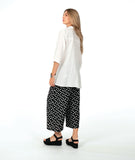 model in a white button down with a swirl texture. blouse has 3/4 sleeves and oversized rounded pockets at the hip. Worn with a wide leg black pant with white polkadots