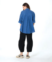 model in a black pant with a checkered blue and grey print button down blouse with rolled sleeves
