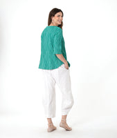 model in a barrel leg white pant with a matching teal pullover top with a 3/4 sleeve and an open flat collar