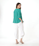 model in a barrel leg white pant with a matching teal pullover top with a 3/4 sleeve and an open flat collar