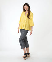 model in a yellow pullover top with 3/4 sleeves, a collar and a deep v. worn with a slim grey crop pant