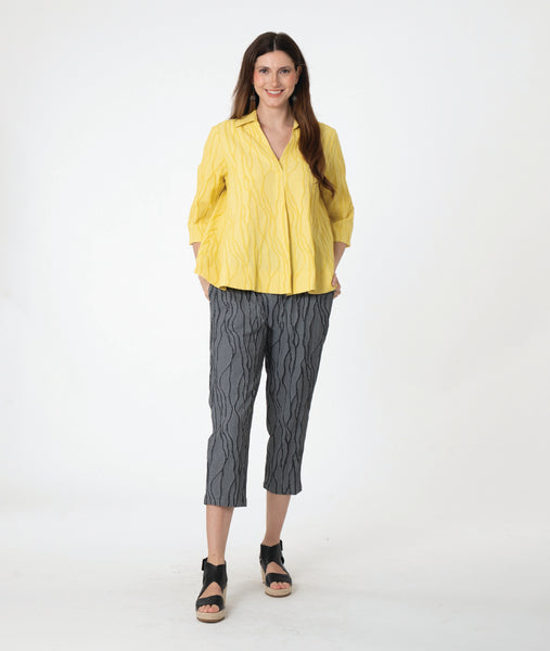 model in a yellow pullover top with 3/4 sleeves, a collar and a deep v. worn with a slim grey crop pant