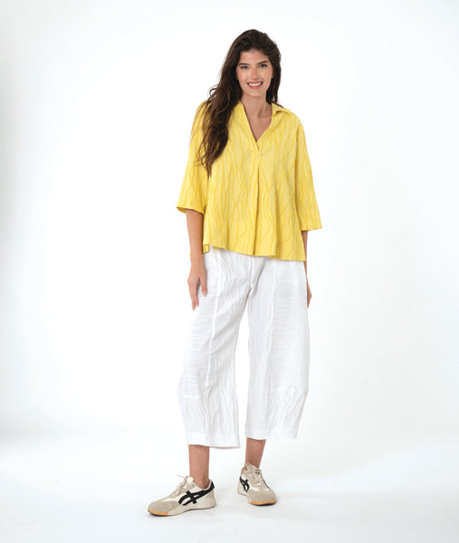 model in a white barrel leg pant with a matching yellow pullover top with 3/4 sleeves, a collar and a vneck