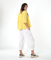 model in a white barrel leg pant with a matching yellow pullover top with 3/4 sleeves, a collar and a vneck