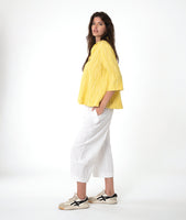 model in a white barrel leg pant with a matching yellow pullover top with 3/4 sleeves, a collar and a vneck