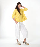 model in a white barrel leg pant with a matching yellow pullover top with 3/4 sleeves, a collar and a vneck
