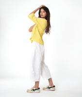 model in a white barrel leg pant with a matching yellow pullover top with 3/4 sleeves, a collar and a vneck