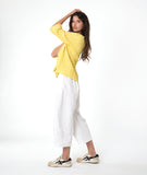 model in a white barrel leg pant with a matching yellow pullover top with 3/4 sleeves, a collar and a vneck