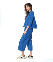 model in a blue button down blouse with a twin button detail and 3/4 sleeves. worn with a matching straight leg cargo pant