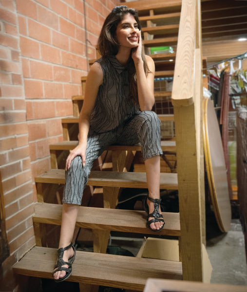 model in a grey sleeveless top with a twin button detail, worn with a matching slim crop pant