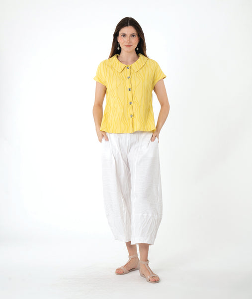 model in a white barrel pant with a yellow button down blouse with a round collar and a cap sleeve