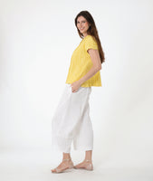 model in a yellow button down blouse with cap sleeves. worn with a white barrel leg pant 
