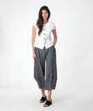 model in a white button down blouse with cap sleeves. worn with a grey barrel leg pant 