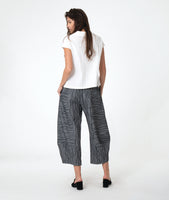 model in a white button down blouse with cap sleeves. worn with a grey barrel leg pant 