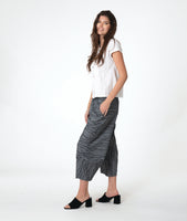model in a white button down blouse with cap sleeves. worn with a grey barrel leg pant 