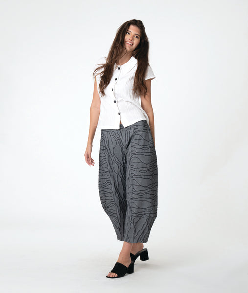 model in a white button down blouse with cap sleeves. worn with a grey barrel leg pant 